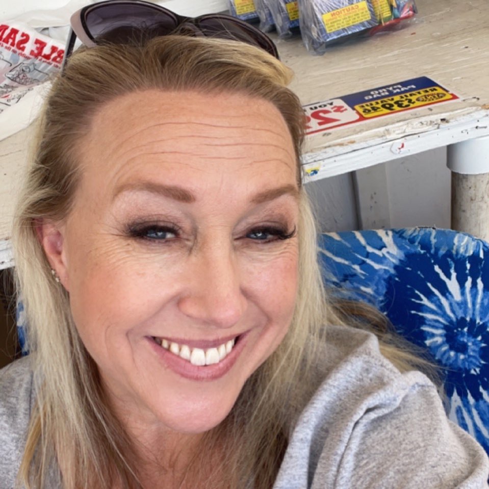 up close picture of smiling blonde woman with sunglasses on head